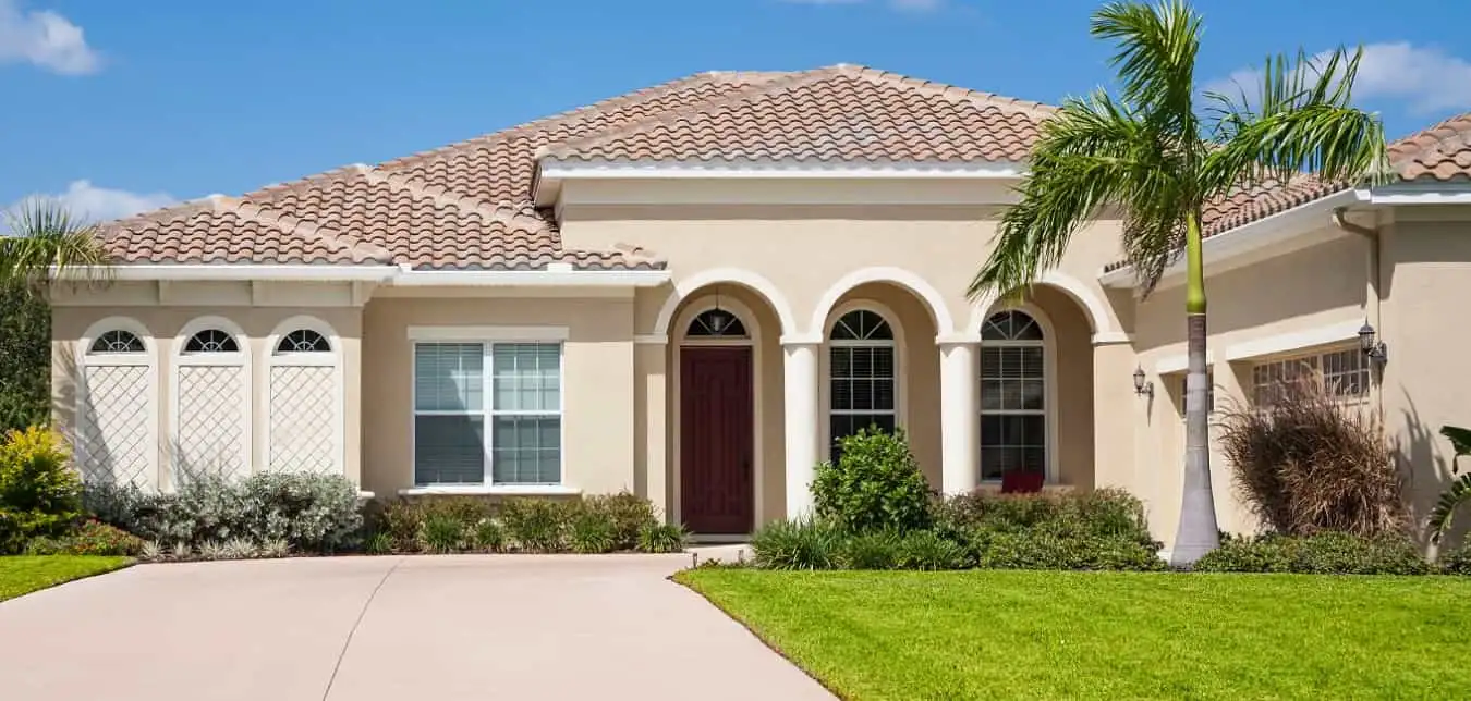 Mediterranean-style home with an arched entrance, tile roof, and palms